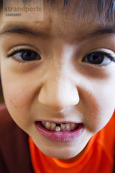 Ein sechsjähriger japanisch-amerikanischer Junge zeigt uns seinen losen Zahn.