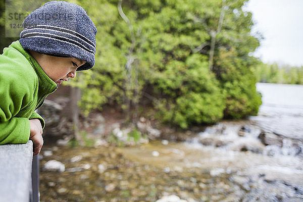 Ein 4 Jahre alter japanisch-amerikanischer Junge schaut über den Rand einer hölzernen Fußgängerbrücke entlang des Georgian Bay Trail  während er den Bruce Peninsula National Park  Ontario  Kanada  erkundet.