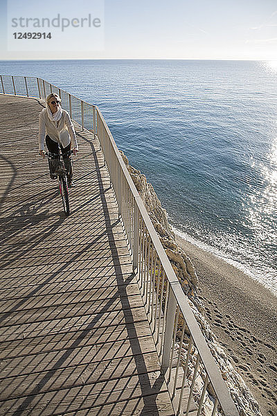 Erhöhte Perspektive einer Frau auf einem Fahrrad am Meer