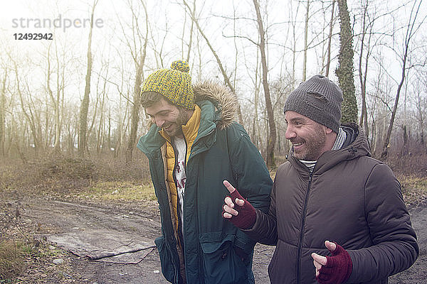 Zwei männliche Freunde unterhalten sich beim Spaziergang im Wald
