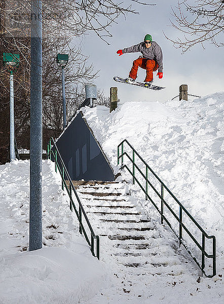 Männlicher Snowboarder springt über eine Treppe in New England