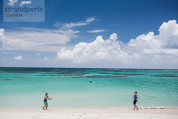 Ein Mann und eine Frau werfen einen Fußball auf dem weißen Sandstrand der Karibikinsel Anegada.