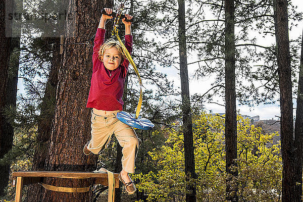 Ein junges Mädchen springt von einer hohen Plattform  während sie in ihrem Garten in Durango  Colorado  mit der Seilrutsche fährt.