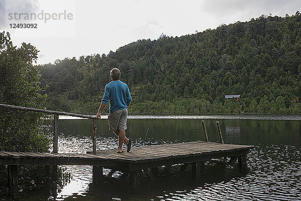 Mann schaut vom Holzsteg über den See