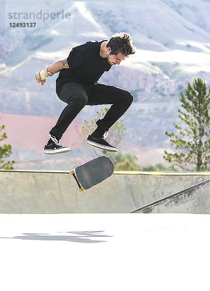Mann vollführt Kickflip beim Skateboarden auf flachem Boden