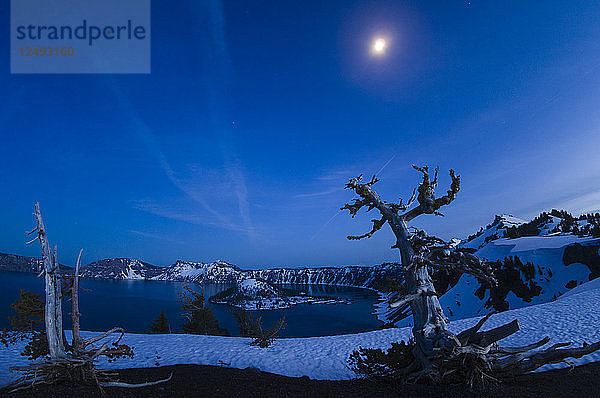 Der Mond geht in einer Winternacht über dem verschneiten Crater Lake  Oregon  auf.