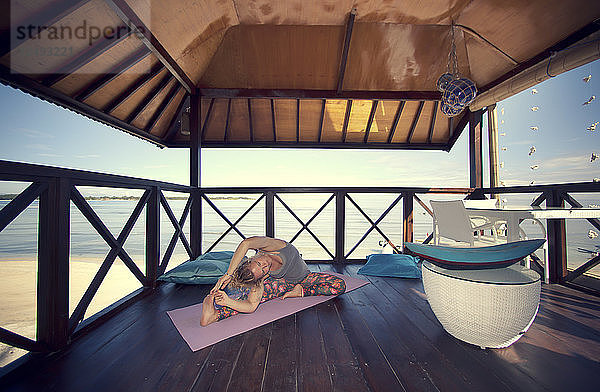 Schönes Mädchen am Strand macht Yoga auf der Terrasse. Indonesien Gili Insel