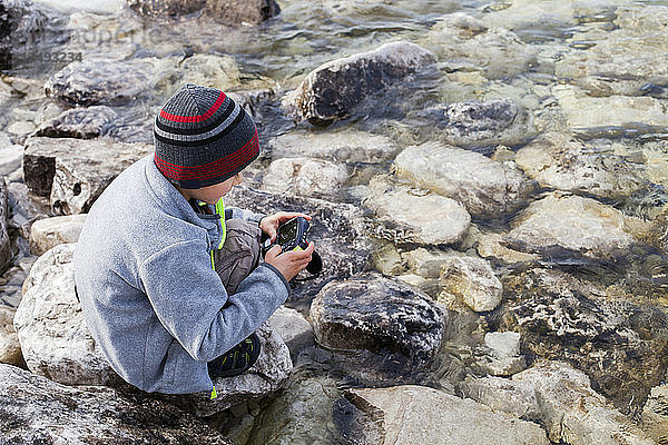 Ein 6-jähriger japanisch-amerikanischer Junge macht ein Foto im Wasser des Huron-Sees  während er die Grotte im Bruce Peninsula National Park  Ontario  Kanada  erkundet.