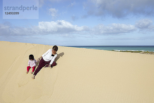 Mutter und Tochter spielen im Sand in Playa De Sotavento  Spanien