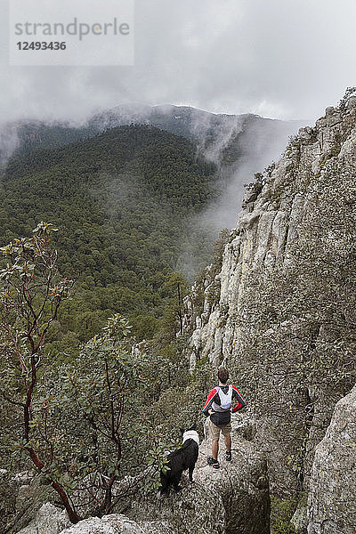Mann mit seinem Hund  der auf einem Felsen steht und die Landschaft betrachtet  Rancho Santa Elena  Hidalgo  Mexiko