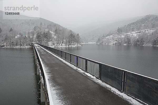 Einspurige Brücke über Bergsee  ferne Hügel und Sturm