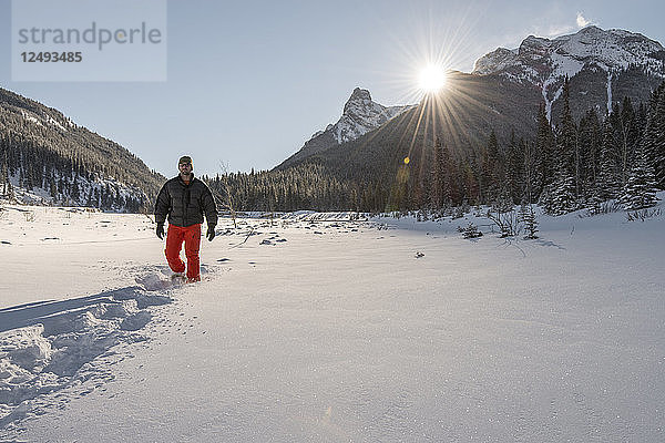 Mann auf Schneeschuhen durch verschneiten Wald  Berge