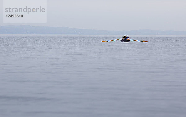 An einem nebligen Tag auf dem Skaneateles Lake rudert eine Frau ihr Adirondack-Führerboot in den Nebel.