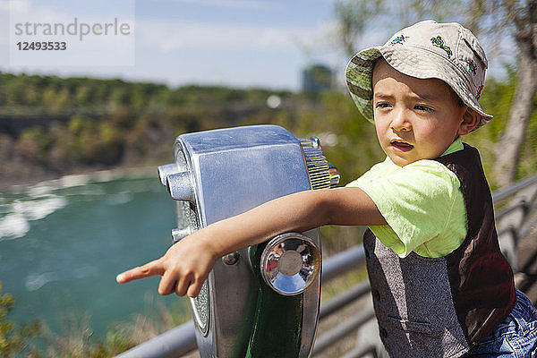 Ein 4-jähriger japanisch-amerikanischer Junge zeigt auf ein kostenpflichtiges Teleskop an den Niagarafällen  New York.