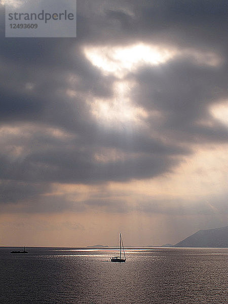 ein Segelboot  bewölkter Himmel  die Sonne geht unter