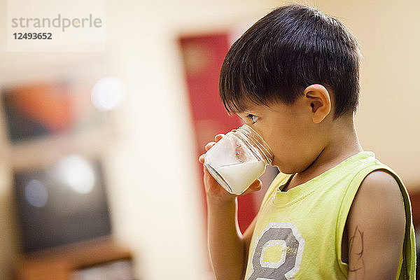 Ein vierjähriger japanisch-amerikanischer Junge trinkt ein Glas Milch.