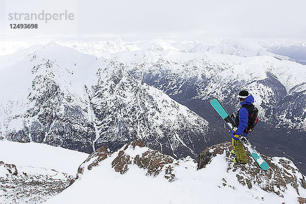 Ein Skifahrer steht auf einem felsigen Berg mit Blick auf die Anden vom Cerro Catedral in Argentinien