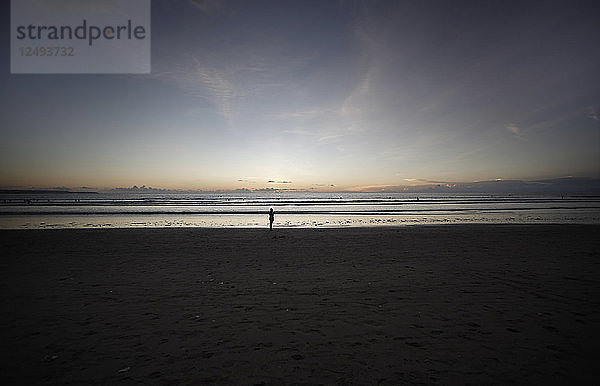 Sonnenaufgang Menschen  die am Strand spazieren gehen.Indonesien Bali Kuta