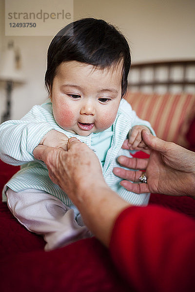 Eine Großmutter hält ihr 4 Monate altes japanisch-amerikanisches Mädchen im Arm.