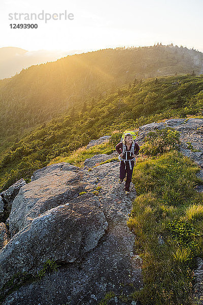 Eine Frau wandert bei Sonnenuntergang auf Grassy Ridge während einer Rucksacktour in den Roan Highlands in der Nähe von Bakersville  North Carolina.