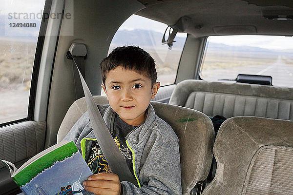 Ein siebenjähriger Junge sitzt in einem Vorort auf einer Fahrt durch Nevada und liest.