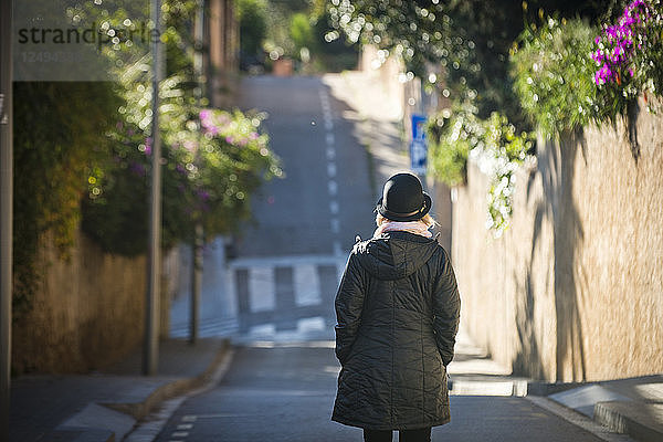 Ein Mädchen geht an einem sonnigen Tag in Barcelona  Spanien  eine bunte Straße entlang.