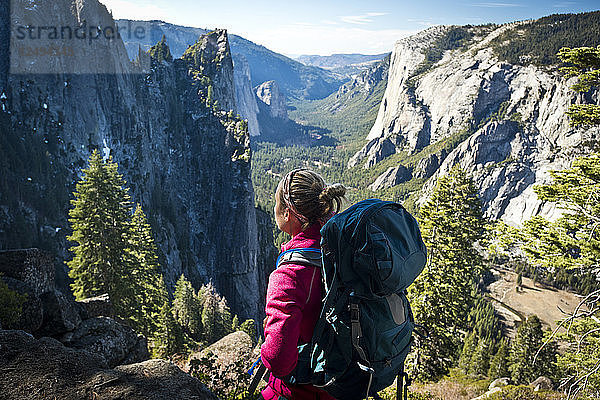 Eine Rucksacktouristin macht an einem sonnigen Tag eine Pause  um die Aussicht auf den Yosemite-Nationalpark zu genießen.