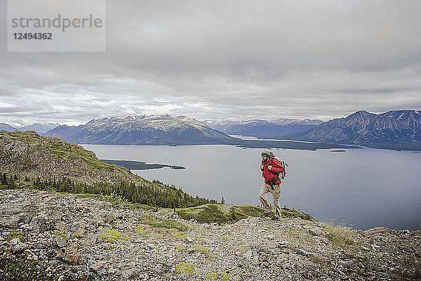 Männlicher Wanderer auf dem Monarch Mountain mit Blick auf den Atlin Lake und die Boundary Mountain Ranges British Columbia