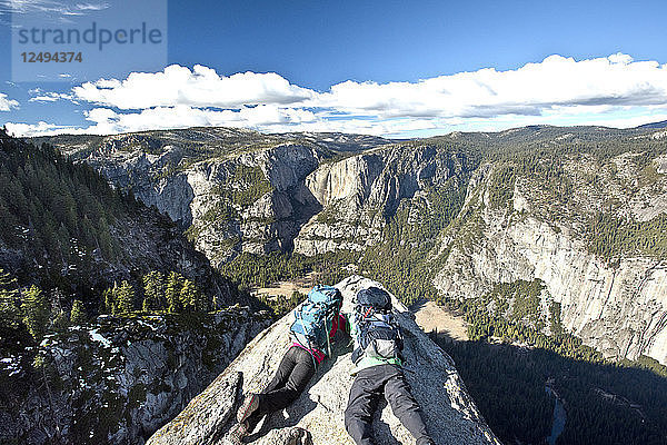 Zwei Rucksacktouristen liegen auf einer Felsklippe am Glacier Point mit Blick auf den Yosemite National Park.