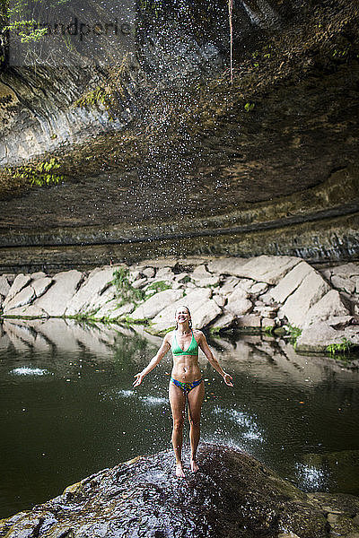 Eine junge Frau vergnügt sich an einem heißen Tag im Hamilton Pool in der Nähe von Wimberley  Texas.