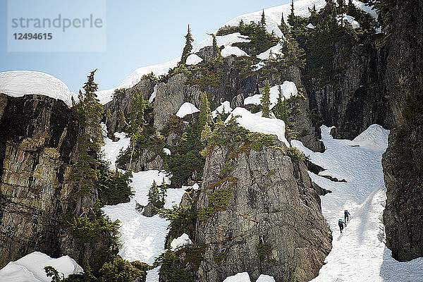 Zwei Rucksacktouristen klettern eine schneegefüllte Schlucht hoch in den Bergen von British Columbia  Kanada.