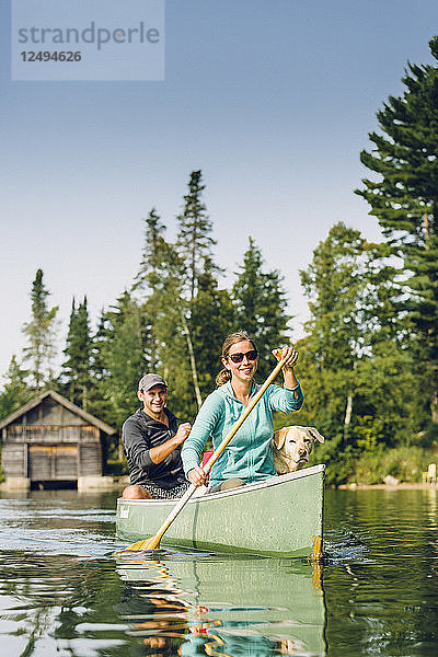 Lächelnder Mann und Frau Kanufahren mit ihrem Hund auf dem Kaspischen See