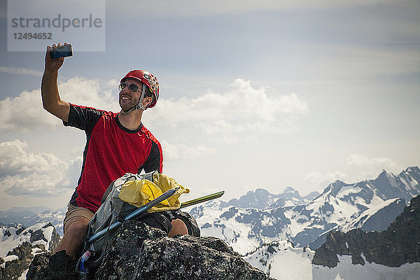 Ein Bergsteiger macht ein Selfie mit seinem Smartphone auf dem Gipfel des Trio Peak in British Columbia  Kanada.