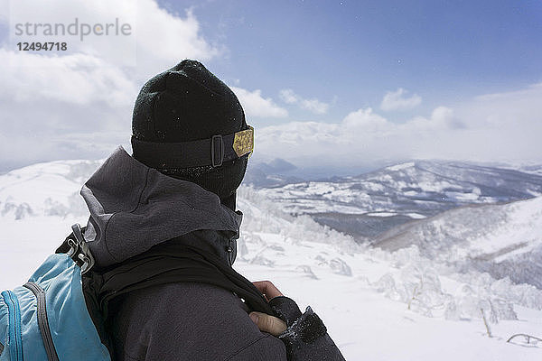 Snowboarder  der auf dem Gipfel eines Berges steht und Niskeo  Japan  erkundet