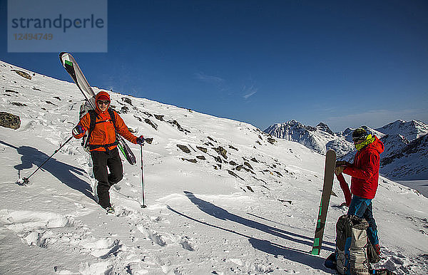 Skifahrer fahren während der Spearhead Traverse in den Coast Mountains von British Columbia  Kanada  einen Schneehang voller Felsen hinunter.