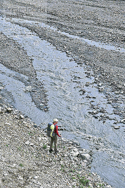 Eine Rucksacktouristin überquert den Sunrise Creek im Tal des Thorofare River im Denali National Park & Preserve  Alaska  Juli 2011. Im Hintergrund ist der Mount Eielson zu sehen. Ein großer Teil der Wanderungen im Park verläuft ohne Wege und zwingt die Wanderer  Bachbetten und Flusstäler zu bevorzugen. (Modellfreigabe: Agnes Hage)
