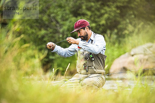 Ein Fliegenfischer bereitet seine Ausrüstung vor  während er neben dem Yampa River in Colorado sitzt.