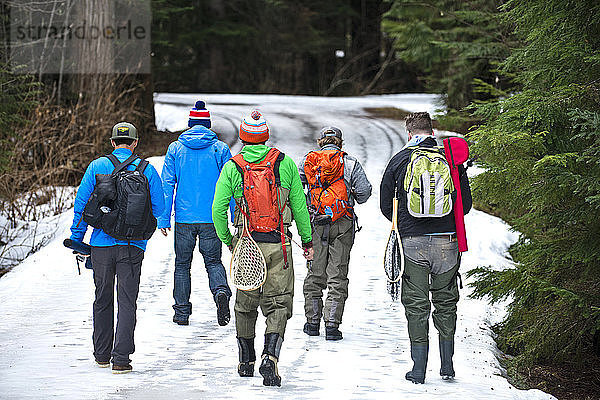 Eine Gruppe von Freunden in Angelausrüstung geht eine Bergstraße in Squamish  British Columbia  hinunter.