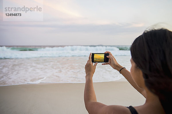 Frau  die ein Bild von den Wellen macht  die sich dem Ufer am Strand von Copacabana nähern