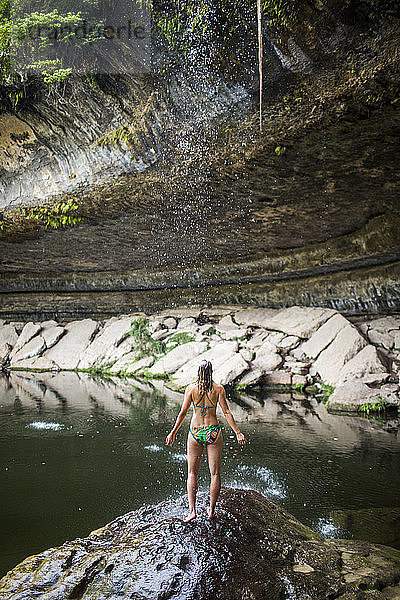 Eine junge Frau vergnügt sich an einem heißen Tag im Hamilton Pool in der Nähe von Wimberley  Texas.