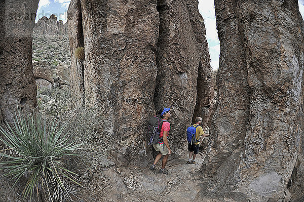 Ein Mann und eine Frau erkunden die Felsformationen am Fremont Saddle auf dem beliebten Peralta Trail in der Superstition Wilderness Area  Tonto National Forest in der Nähe von Phoenix  Arizona  November 2011. Der Weg bietet spektakuläre Ausblicke auf Weavers Needle und die raue Sonoran-Wüste.