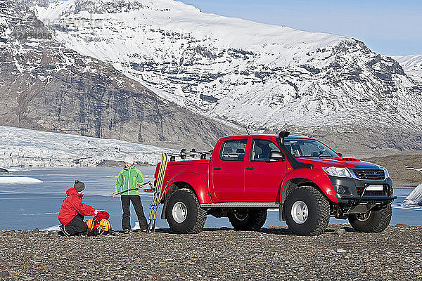 Pärchen macht sich bereit für eine Skitour vor einem maßgeschneiderten SUV / isländischen Superjeep