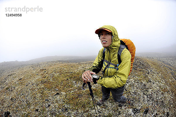 Eine Wanderin navigiert mit einem GPS-Gerät durch die Flanken des Homocide in der vorderen Bergkette der Chugach Mountains in Anchorage  Alaska  August 2011.