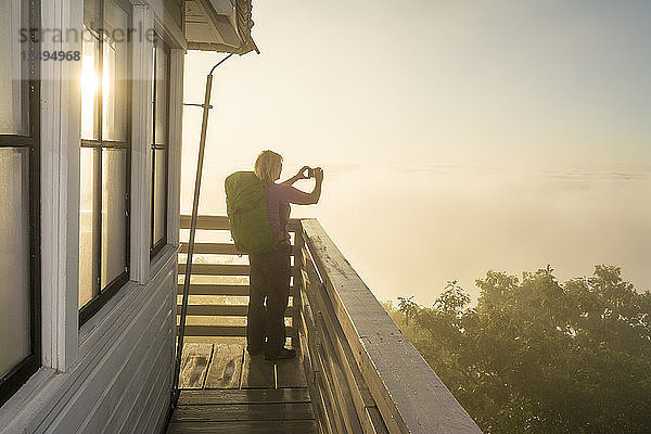 Eine Frau genießt die Aufnahme von Bildern während eines nebligen Morgens am Green Knob Firetower