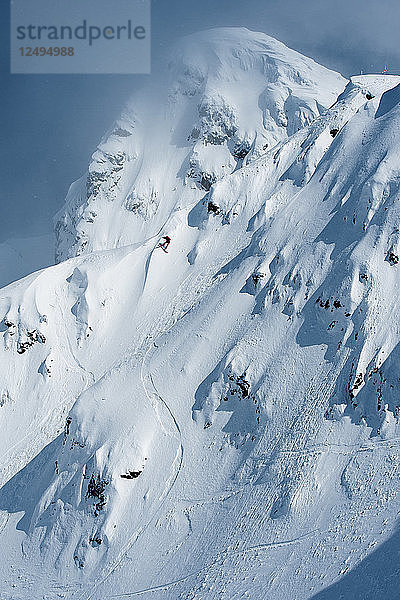 Snowboarder fährt einen Abhang eines verschneiten Berges hinunter