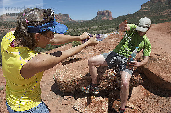 Ein Paar spielt mit Wasserflaschen auf dem Cathedral Rock Trail in Sedona  Arizona. Der Weg über glatten Sandstein führt zu einer beliebten Felsengruppe oberhalb von Sedona.