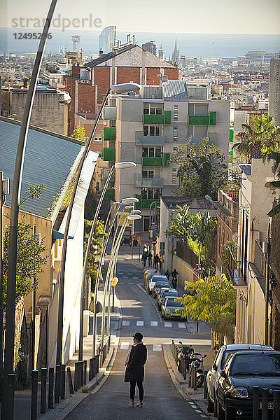 Ein Mädchen geht an einem sonnigen Tag in Barcelona  Spanien  eine leere Straße entlang.