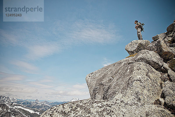 Ein Wanderer steht auf einem Granitfelsen in der Nähe des Gipfels von Needle Peak.
