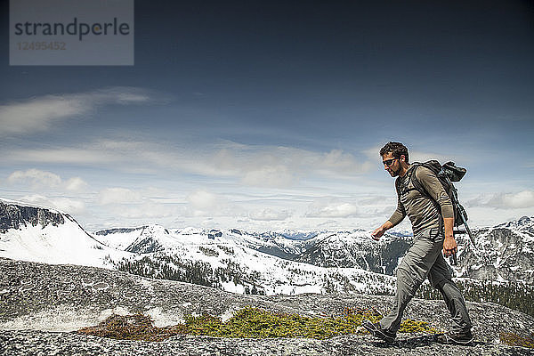 Ein Rucksacktourist wandert über Granitfelsen in einem subalpinen Gelände.