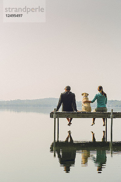 Mann und Frau mit ihrem Hund sitzen auf Dock auf Kaspischen See